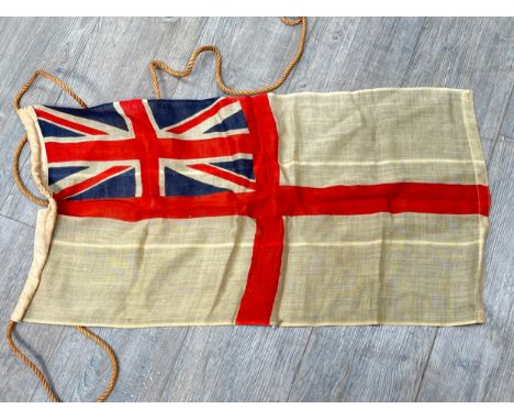 A vintage British White Ensign flag, 82cm x 44.5cm, together with a 1940 dated Brodie helmet shell and a late war / 1950’s Br