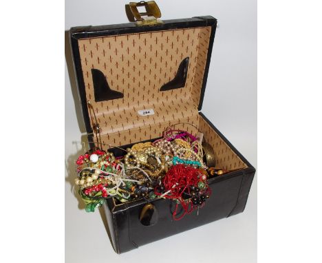 A black leather vanity case containing mid 20th century costume jewellery including faux pearl, bead, gold &amp; silver plate