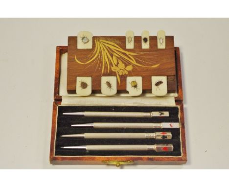 An early 20th century cased set of four sterling silver propelling pencils/ bridge scoring markers terminating in applied pla