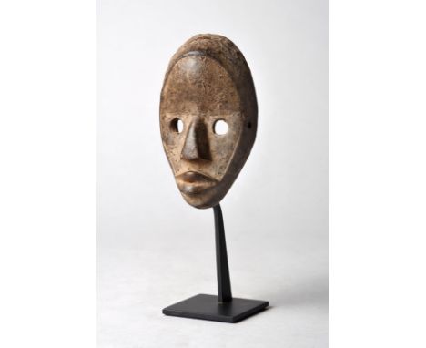 A Dan passport mask Ivory Coast with an encrusted patina, 13cm high, on a stand. (2) Provenance Private Collection, Los Angel