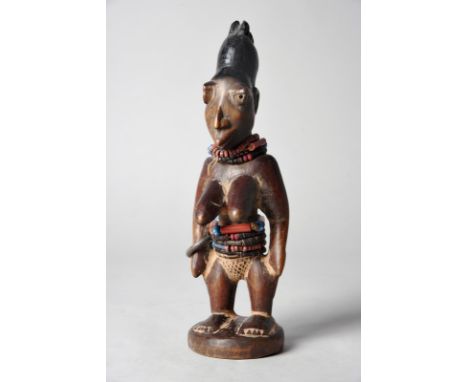 A Yoruba female Ibeji figure Oro/Omu Aran, Igbomina, Nigeria wearing bead necklaces and waist bands and a lead bangle, 27.5cm