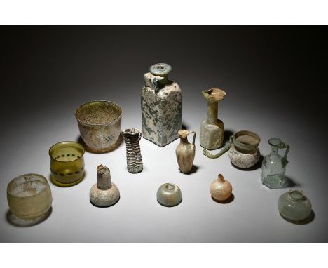 A collection of Roman glass vessels circa 1st - 5th century AD including a square bottle with moulded concentric circles to t
