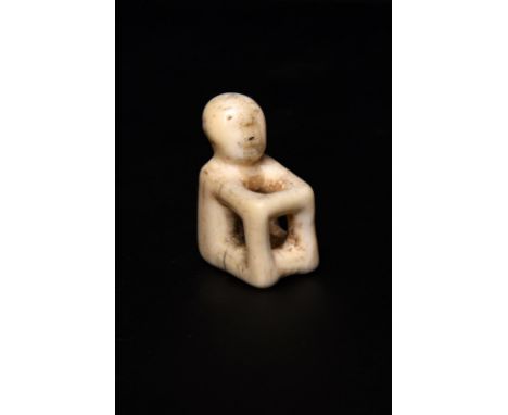 λAn Aleutian seated figure amulet Bering Sea, Alaska walrus ivory, of open cube form with carved facial features and pierced 