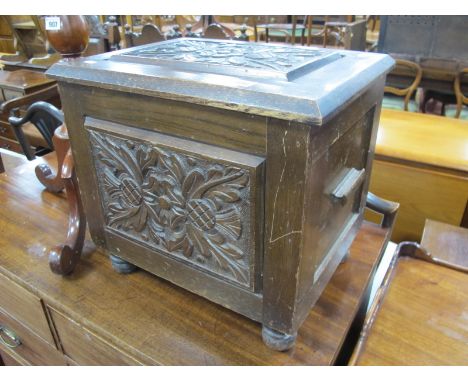 An Early XX Century Oak Coal Box,  with a hinged carved top and front panel, on turned feet.