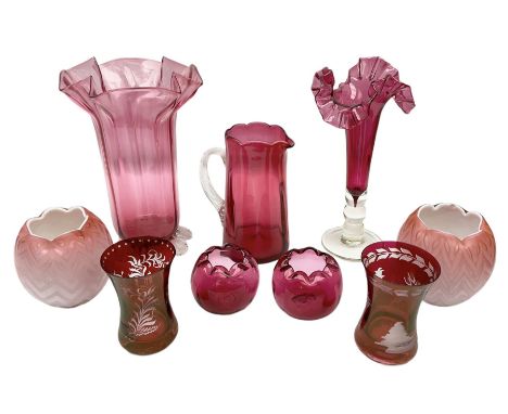 Group of cranberry glass, to include trumpet vases, with crimped decoration, jug with a clear glass handle, large vase with c