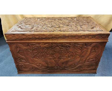 An early 20th century Chinese camphor chest, with carved dragon design to the lid and sides, the front with dragons chasing t