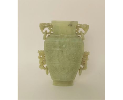 A Chinese celadon jade taotie vase, of tapered form with dragon handles and hanging hoops, the front and back with raised arc