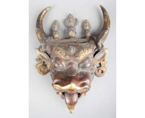 A SINO-TIBETAN PATINATED BRONZE AND PARCEL GILT BULL MASK19th century, modelled in grotesque expression with open mouth beari