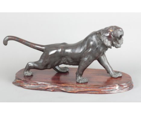 A JAPANESE BRONZE TIGER signed to the underside, Meiji period, figured naturalistically roaring in stride, 21cm high x 45cm w