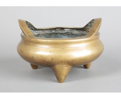 A CHINESE BRONZE TRIPOD CENSERbearing a Xuande mark to the base but probably Qing dynasty, with loop handles to the rim, 8.5c