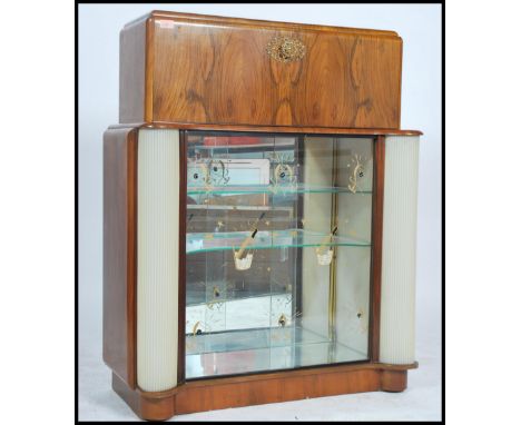 A 1950's post war Art Deco cocktail cabinet having a metamorphic opening top with fully appointed interior having mirror lini