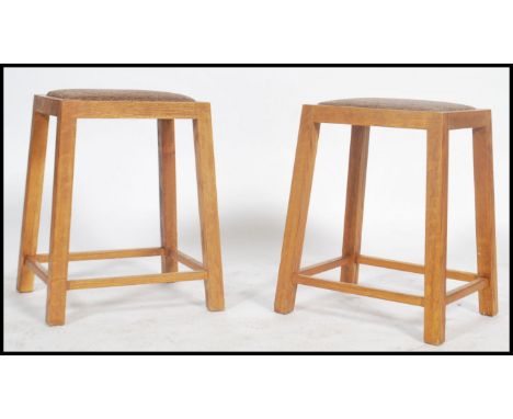 A pair of vintage 20th century wooden oak stools having upholstered seats raised on tapering angular supports.50x 43 x35cm