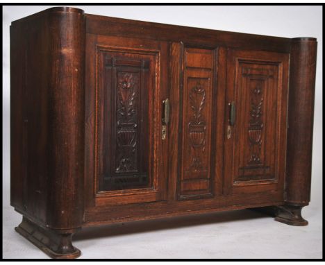 A large early 20th century Art Deco oak sideboard of large, Flemish form and origin having twin doors with carved details