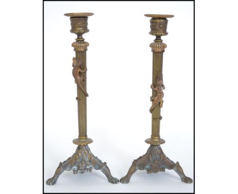 A pair of 19th century Art Nouveau brass candlesticks of column form raised or naturalistic tripod bases with bell sconces to