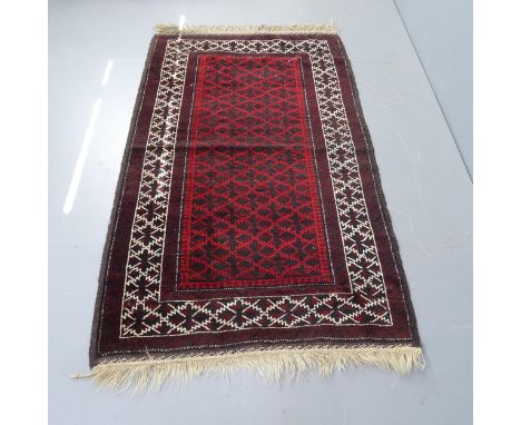 A vintage Afghan wool rug with symmetrical pattern border and central panel, 190cm x 112cm. 