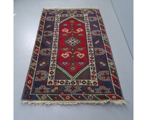 A vintage Turkish red and blue ground rug, 87cm x 115cm. 