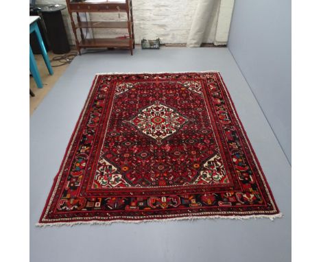A vintage Persian handmade wool red ground rug, 220cm x 165cm. 