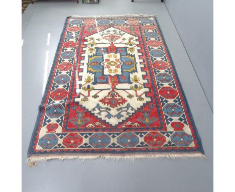 A vintage Turkish wool rug in red, blue and cream, 233cm x 148cm. 