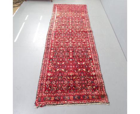 A vintage Persian wool red ground runner, 298cm x 91cm. 