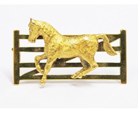 A 9ct gold equestrian brooch formed as a horse by a gate, length 3.7cm, wt. 9.1g