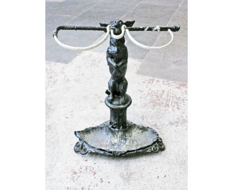 A Victorian cast iron stick stand formed as a dog on its hind legs gripping a riding crop in its jaws standing above the lill
