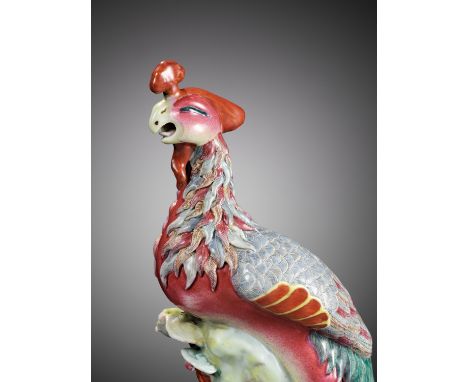 A FAMILLE ROSE FIGURE OF A PHOENIX, 19TH CENTURY 十九世紀粉彩鳳凰China. Perched on a rockwork base issuing lingzhi, the head turned s