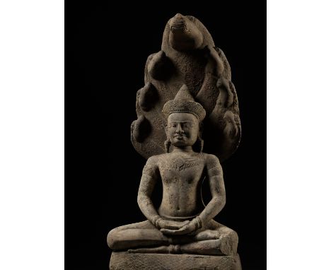 A LARGE SANDSTONE FIGURE OF BUDDHA MUCHALINDA, ANGKOR PERIODKhmer Empire, 12th-13th century. Seated on the scaled coils of Mu