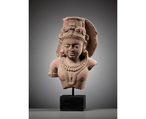 A PINK SANDSTONE BUST OF VISHNU, MADHYA PRADESHIndia, 8th-9th century or slightly earlier. The round face finely carved with 