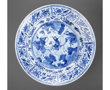 A LARGE BLUE AND WHITE 'HUNTING SCENE' DISH, KANGXI PERIOD 康熙時期青花開光《狩獵圖》大盤China, 1662-1722. The shallow rounded sides rising 