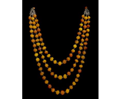 An unusual vintage Baltic amber necklace, c1930, fastened to the front with three rows of ovoid amber beads, connected by gil