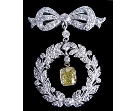 A belle epoque diamond and fancy yellow and platinum brooch/pendant, the bow design top suspending a platinum and diamond wre