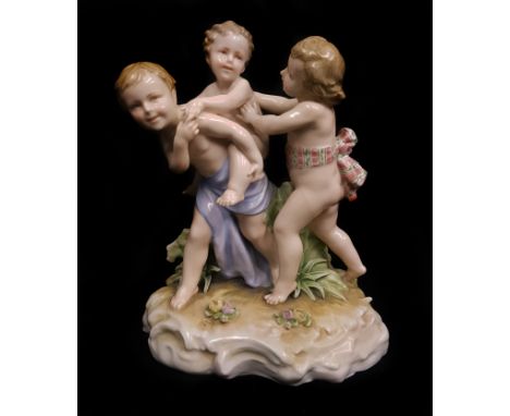 A Continental porcelain group of three children playing at piggy back rides, applied florets and foliage scrolled rock work b