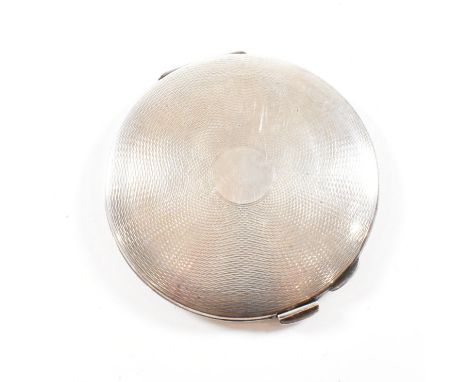 A mid century hallmarked silver compact. The compact having an engine turned design with central vacant cartouche. Hallmarked