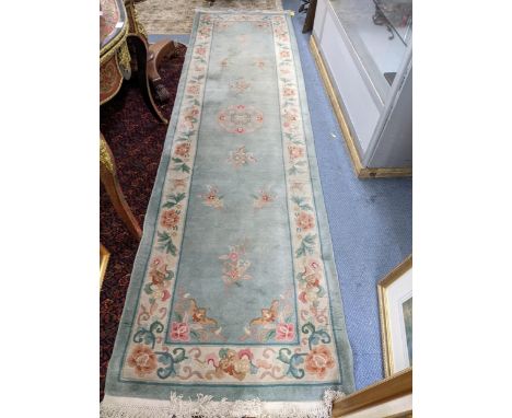 A Chinese floral patterned runner on a light blue and cream ground 321cm x 86cm Location: 