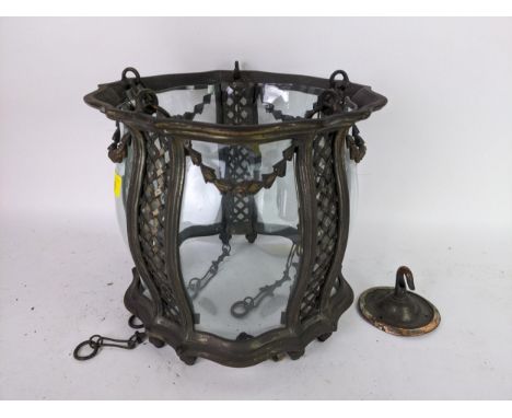 An Edwardian patinated metal framed ceiling light with shaped glass panels, swag and lattice decoration, four metal hanging c