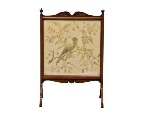 An Edwardian walnut firescreen, with a silkwork of a parrot amidst flowering branches, within a scroll and gadroon carved fra