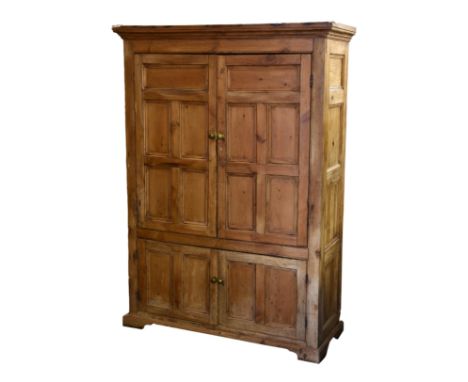 A Victorian stripped pine cupboard, the moulded cornice over four panel sides and a pair of five panel doors enclosing two sh