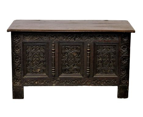 A late 17th century carved and inlaid oak coffer, the three plank top on original hinges, over single panelled sides with hol