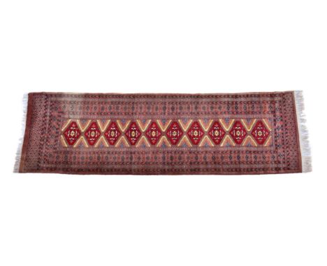 A Tekke style runner, second half 20th century, the main field with ten linked, claret red hexagonal medallions and ochre, or