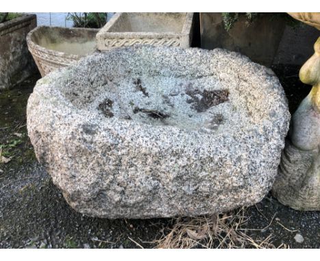 A very old Guernsey granite trough, probably 18th century, of rounded form with shallow well, approx. 27 x 24in., 15in. high.