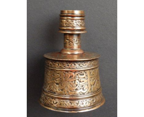 An antique Islamic engraved brass candlestick, of tapering cylinder form decorated stylised Islamic script, 4.5” high