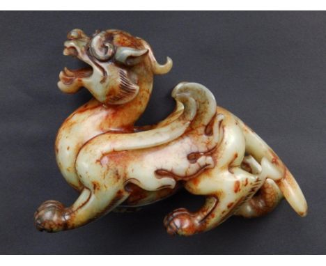 A large Chinese jade dragon, in green & rust colours, in recoiled stance with snarling mouth, 8.5” across SEE ILLUSTRATION