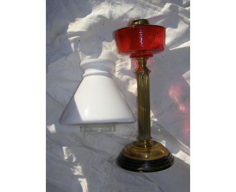 A brass column oil lamp with cranberry reservoir and white glass shade