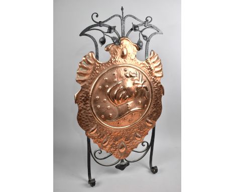 An Arts and Crafts Wrought Iron and Copper Fire Screen, Shield Shaped Copper Panel Decorated with Helmet, Easel Back, 74cms H