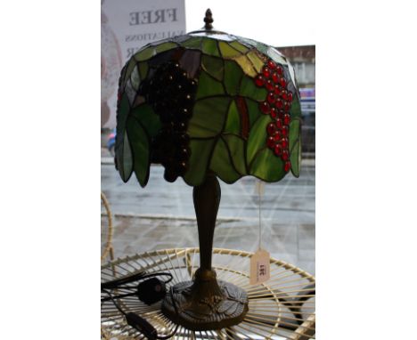 A Tiffany style lamp, the shade leaf decorated with bunches of grapes, on baluster shaped base incorporating dragonflies.
