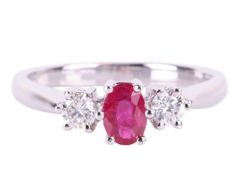 A ruby and diamond three-stone ring, claw-set with an oval mixed-cut ruby measuring approximately 6mm x 4mm, flanked by two r