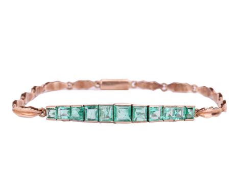 An Art Deco emerald line bracelet, set with a row of eleven graduated calibré cut emeralds, in engraved square settings, to a