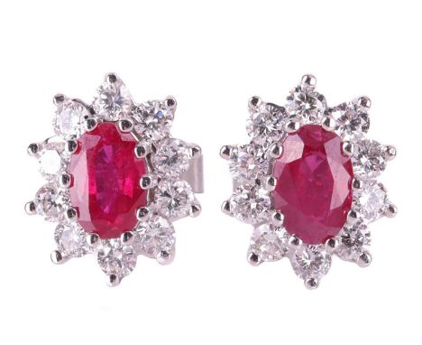 A pair of ruby and diamond cluster earrings, the central oval-cut rubies measuring approximately 6mm x 4mm, and surrounded by