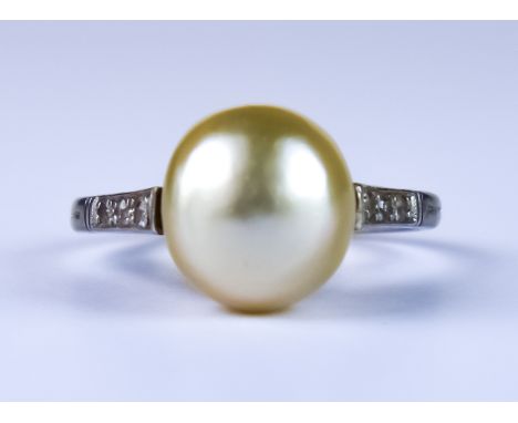 A Button Pearl and Diamond Ring, white metal set with a natural button pearl, approximately 9mm diameter, flanked by six smal