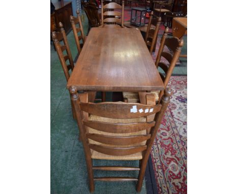 An oak trestle table; six oak ladder back rush seated chairs